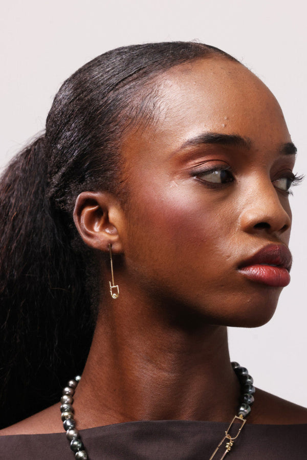 woman wearing a pearl necklace and gold earrings looking to one side